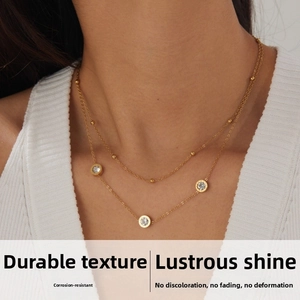 Detail view of double-layer gold stainless steel chain with round zircon pendant on neck