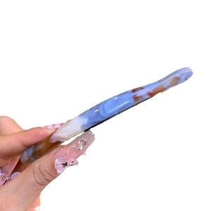 Elegant acetate hair clip with marble texture in blue and white, handheld view