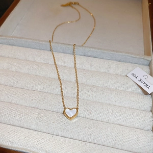 Détail d'un pendentif cœur doré avec nacre blanche dans un coffret à bijoux