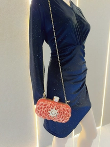 Close-up of red dinner clutch featuring tiered crystal flower patterns and gemstone detail