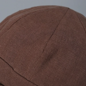 Détail macro du chapeau bob en lin montrant la texture du tissu marron de qualité