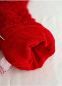 Detail of red knit Christmas stocking showing 100% polyester care label and soft fabric