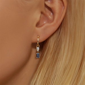 Detail of gold chain tassel earring with blue rectangle stone on model's ear