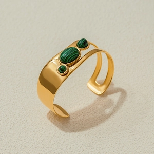 Macro shot of gold wide cuff bracelet featuring three inlaid green malachite stones