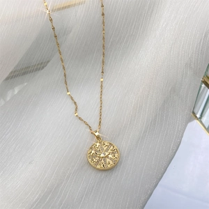 Détail du collier à pendentif disque en or 18K avec motifs étoile, lune, œil et oxydes de zirconium