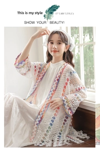 Dettaglio macro del cardigan in pizzo bianco con finiture a frange in stile boho