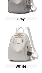 Detail of lychee pattern PU leather backpack with gold zippers and grey pompom charm