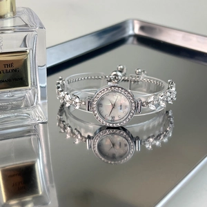 Detailed view of silver leaf-shaped bracelet watch with crystals and mother of pearl dial
