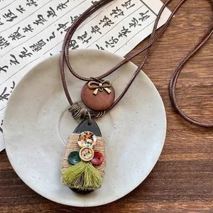Détail d'un collier vintage en perles de bois avec pendentif fleuri et franges vertes