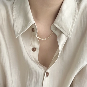 Close-up of minimalist S925 silver golden choker necklace on a delicate textured shirt