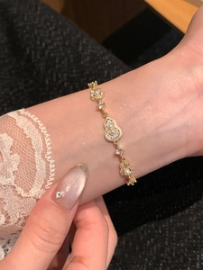 Détail d'une main portant le bracelet gourde plaqué or 18 carats avec perles et zircon