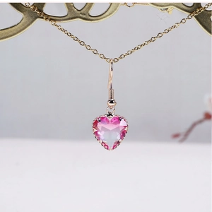 Close-up of rose gold drop earring with faceted pink gradient crystal heart pendant