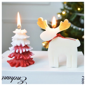 Detail of Christmas tree and white reindeer candles with bells on a white prop book