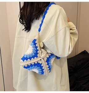 Handcrafted crochet crossbody bag with blue floral patterns shown on a model