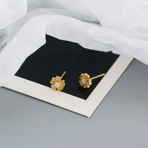 Detail of golden flower zircon stud earrings with five petals on display card