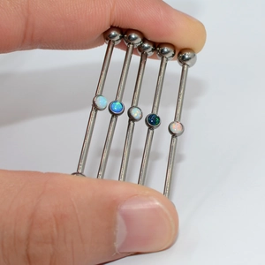 Macro shot of G23 titanium industrial barbell earrings with colorful opal stone inlays
