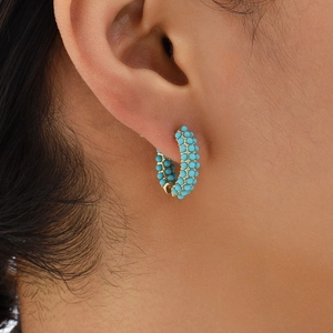 Close-up of golden hoop earrings featuring three rows of turquoise beads on a model