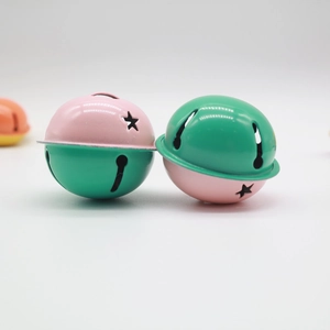 Close-up of 4cm pink and green bicolor metal bells with star cutouts for DIY crafts