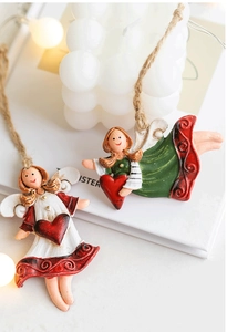 Macro detail of resin Christmas angel ornaments with red hearts and rustic twine loops
