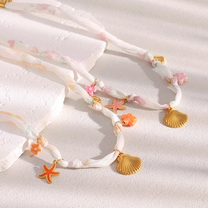 Detail of 18K gold ribbon necklace featuring starfish pendants and seashell charms