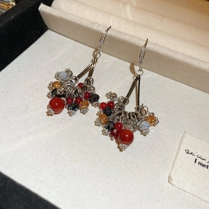 Vue détaillée de boucles d'oreilles vintage à pompons en perles rouges et noires sur velours