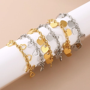 Polished gold and silver heart charms on stainless steel link bracelets displayed on roll