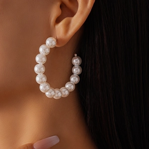 Close-up of elegant white faux pearl beaded hoop earrings worn by a model
