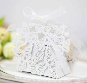 Close-up of white laser-cut butterfly candy box with silk ribbon and hollow pattern
