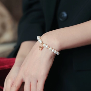 Detailed shot of freshwater pearl bracelet with a golden pinecone charm on a wrist