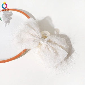 Top view of a large white chiffon bow hair claw clip displayed on a minimalist plate
