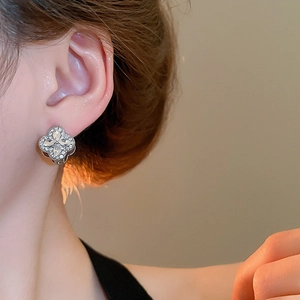 Close-up of sparkling silver clover earring with marquise-cut stones on a model's ear