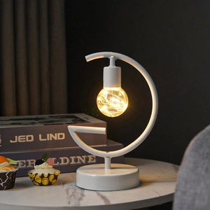 Detail of warm LED moon-shaped wrought iron lamp with hanging copper wire bulb
