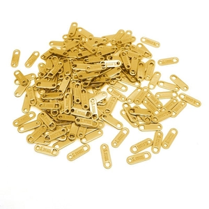 Macro detail of bulk golden S.STEEL engraved oval tag charms for DIY jewelry making