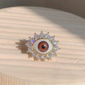 Macro view of gold evil eye ring featuring brown resin iris and sparkling zircon stones