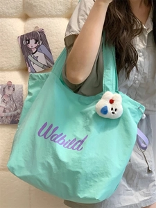 Detail of mint green canvas tote bag with drawstring and cute plush rabbit pendant