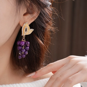 Detail of vintage French style gold leaf earrings with purple beaded grape design on model