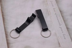 Flat lay of two black metal multi-function beer bottle opener keychains on a desk