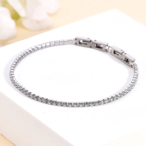 Close-up of silver tennis bracelet with white zircons on a white stone background