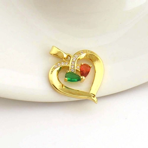 Macro view of gold heart pendant with red and green stones and sparkling zircon pavé