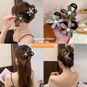 Detail of floral hair claw clip with rhinestones and pearl accent on black resin base