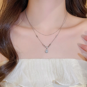 Detail of layered stainless steel necklace with sparkling teardrop pendant on a model