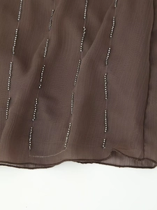 Close-up of brown sequined embroidery and beaded details on summer strapless dress