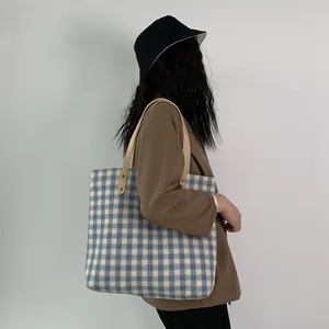 Detailaufnahme der blau-weiß karierten Canvas-Tasche mit Ledergriffen und stabilen Nieten