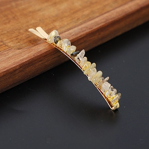 Detail of yellow natural crystal stones set on a golden metallic hair clip on wood
