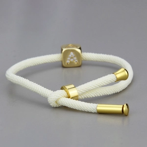 Makroaufnahme: Handgewebtes Armband in Creme mit goldenem Strass-Buchstaben-Anhänger A