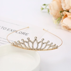 Close-up of golden bridal tiara with sparkling white rhinestones on ceramic tray