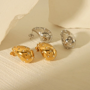 Elegant gold and silver teardrop earrings with pearls and rhinestones on stone background