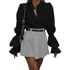 Detailed view of long lantern sleeves on black shirt paired with pleated grey mini skirt