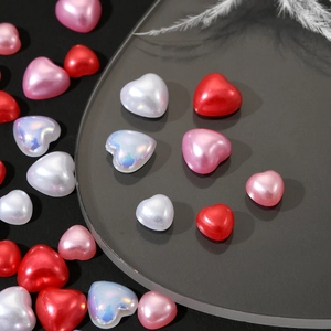 Macro shot of 3D heart-shaped pearl charms in red and pink for DIY nail art and jewelry