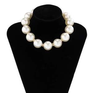 Detailed view of large faux pearl necklace with gold rhinestone spacers on a black display